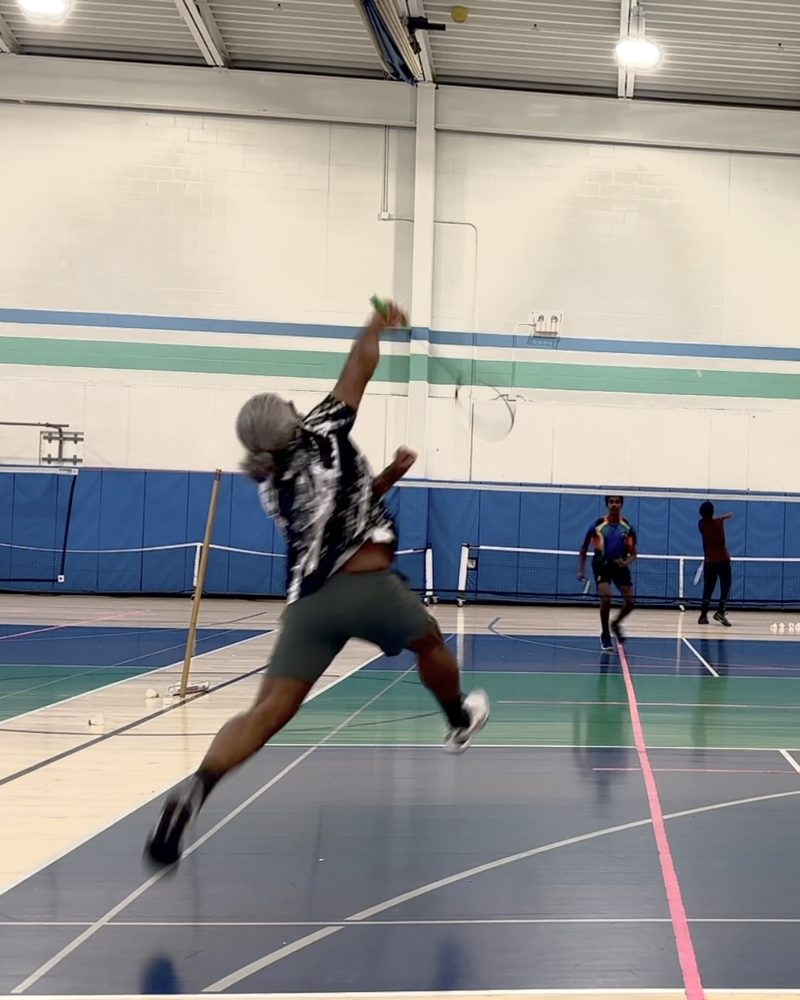 Coach Syam Anand mid-smash on the badminton court